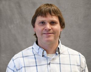 Dr/ Andrus in a white button up shirt smiling for the camera