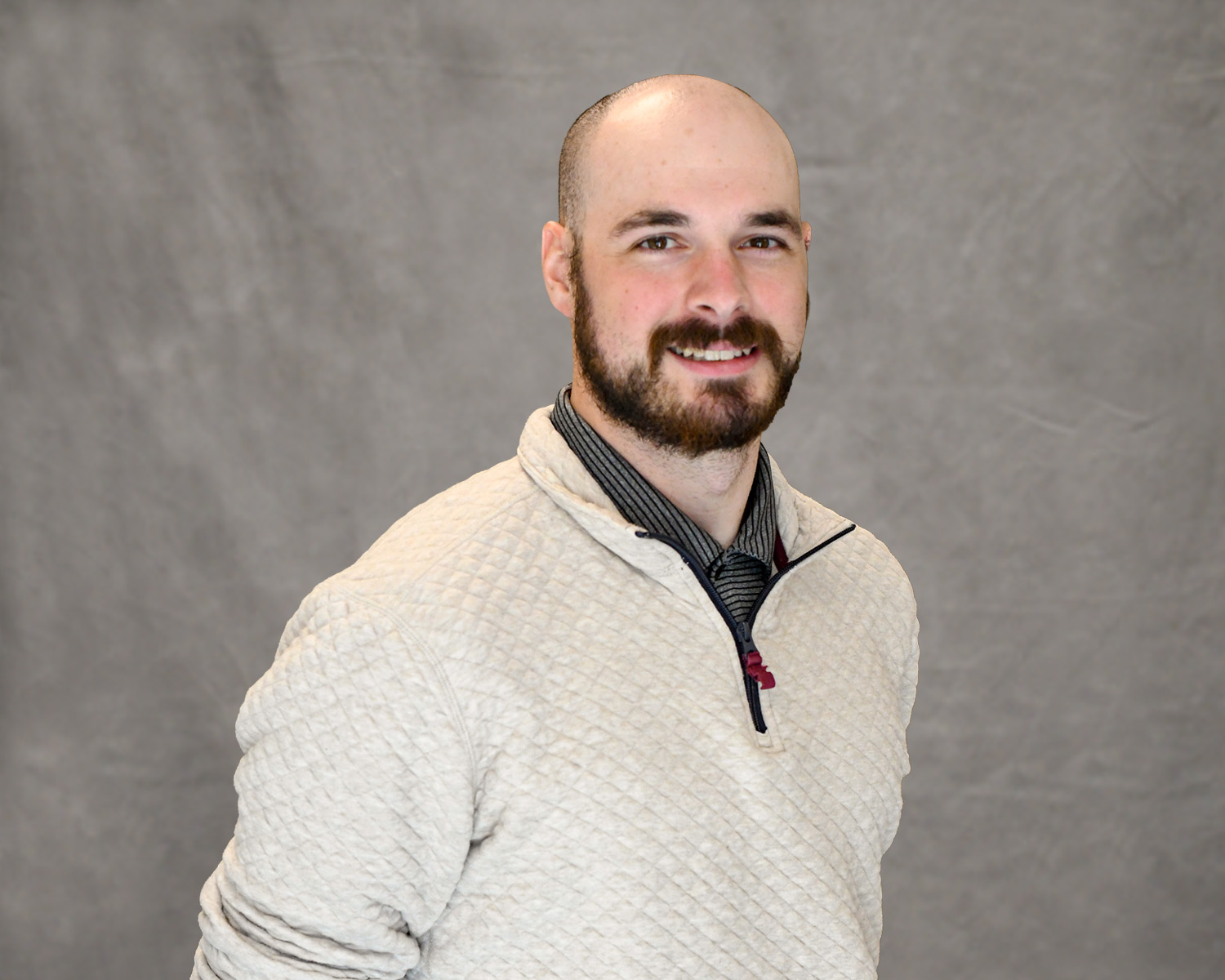 Remington Wurtz is wearing a cream-colored quarter-zip with a green polo shirt underneath, smiling for the camera.