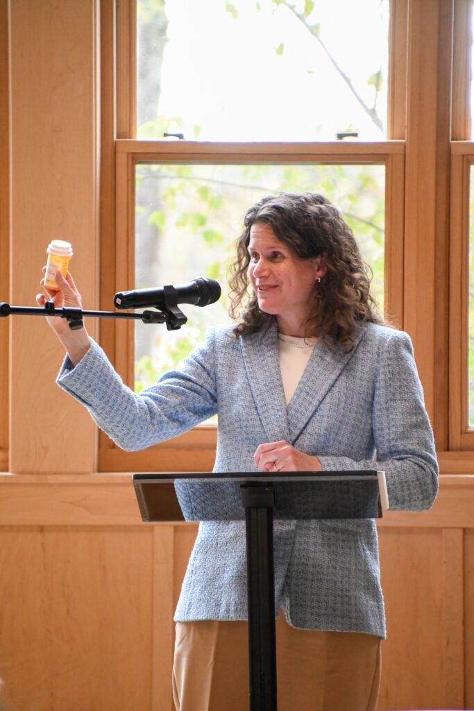Family Health Care CEO Julie Tatko holds a prescription bottle while speaking at the Night of Giving fundraiser.