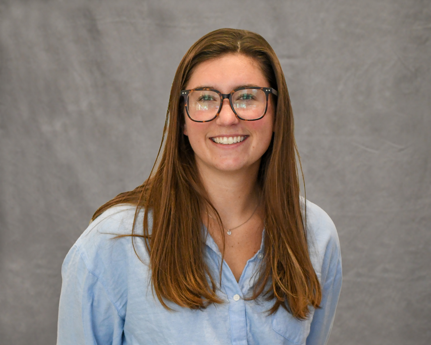 Emma Hanna posing in front of the camera wearing a blue button down shirt.